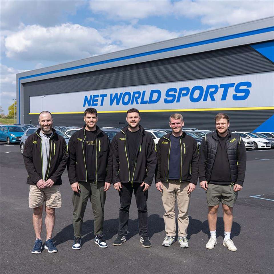 An image of five men posing in front of the Net World Sports Headquarters. 